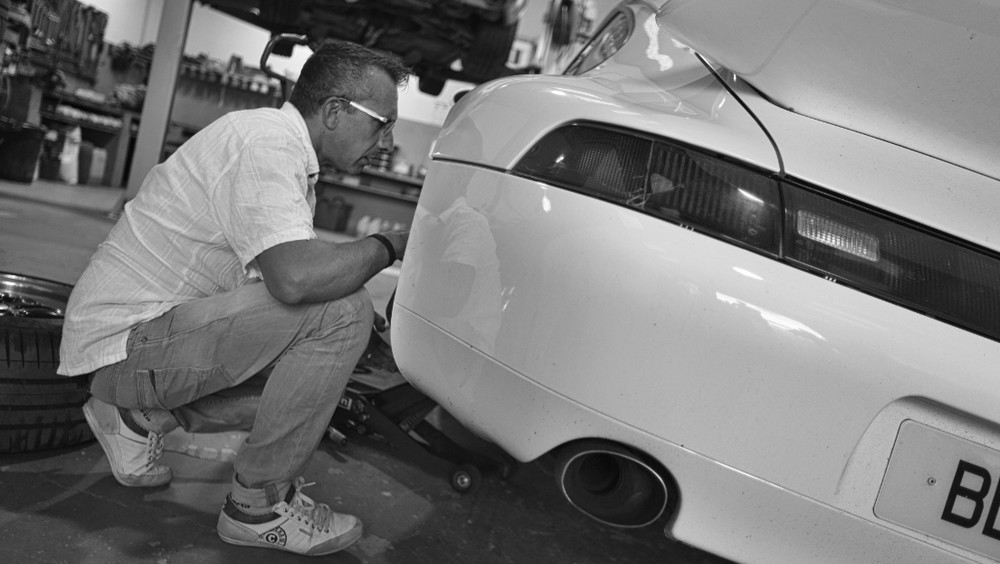 Mécanicien ZKS inspectant l'arrière d'une Porsche 911 blanche